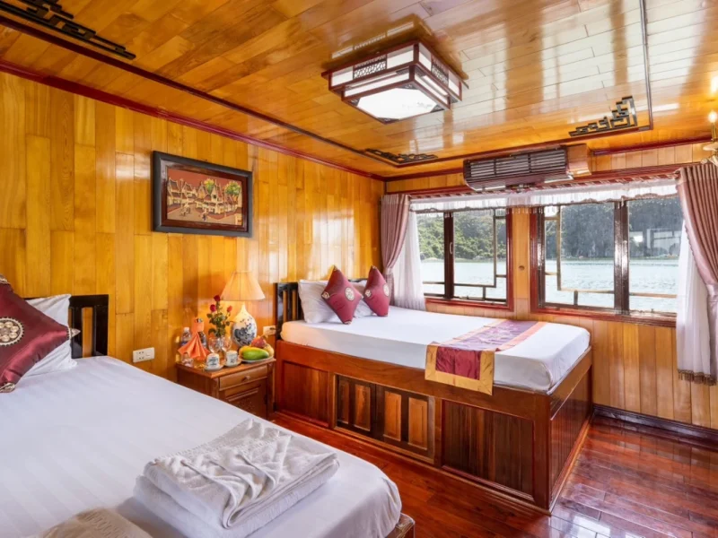 Comfortable twin beds inside a classic wooden cabin during a luxury Lan Ha Bay private cruise